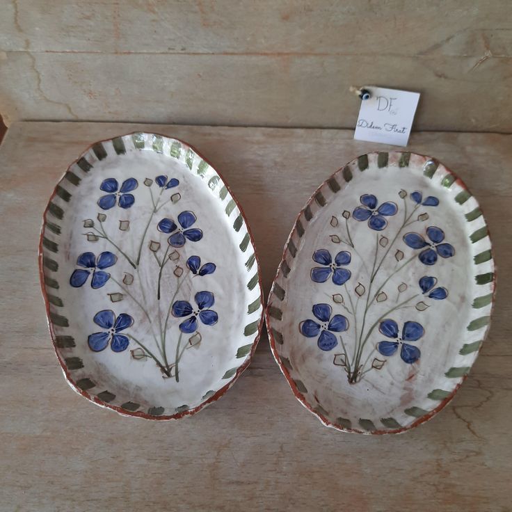 two plates with blue flowers on them sitting on a wooden table next to a price tag