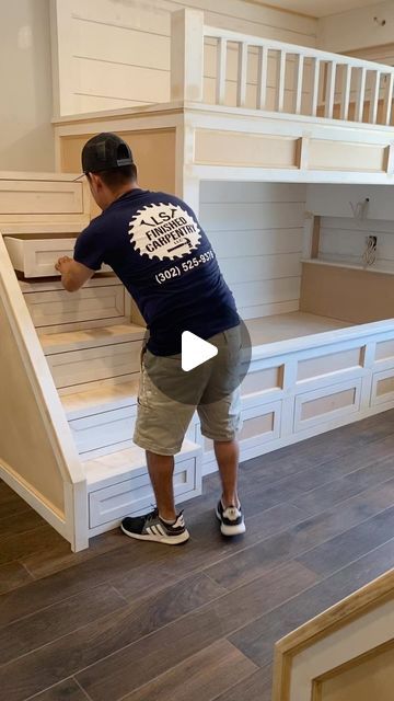 a man standing on top of a wooden floor next to a bunk bed in a room