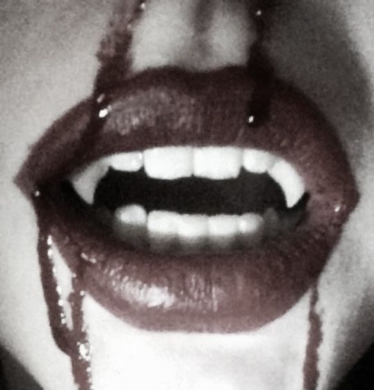 a woman's mouth with beads hanging from the lip and her lips are covered in lipstick