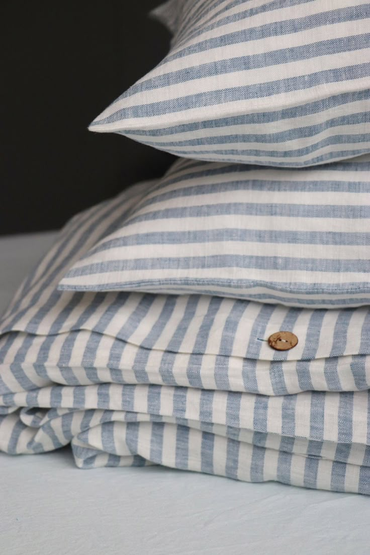 three pillows stacked on top of each other with buttons in the middle one is blue and white