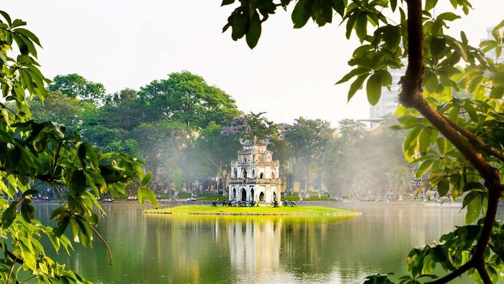 a lake surrounded by trees with a building in the background