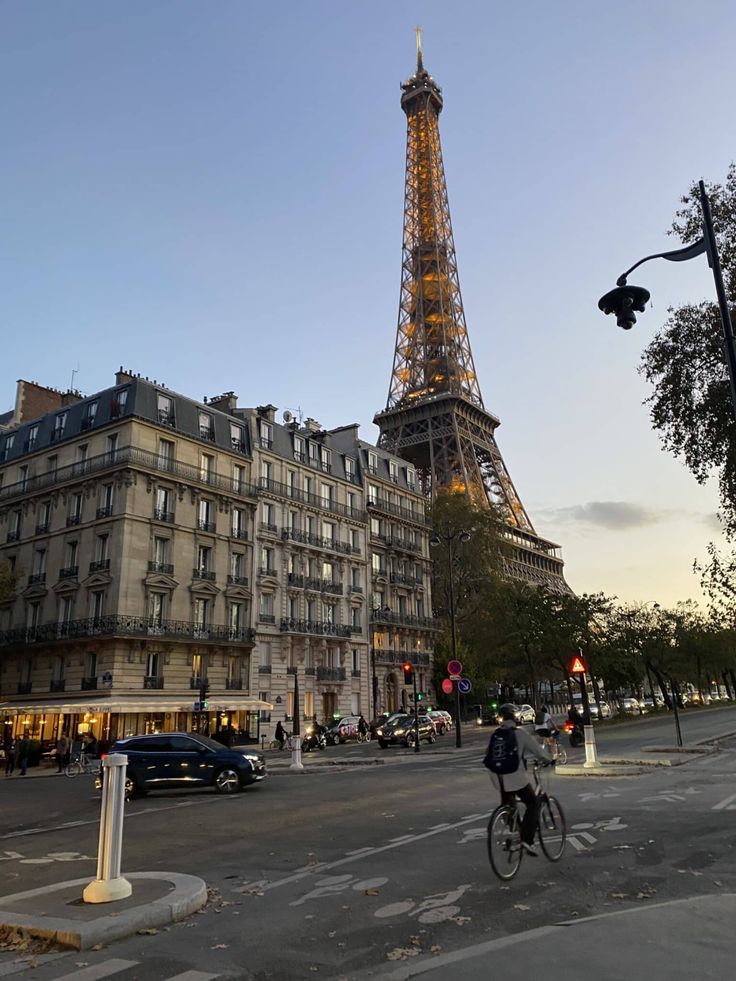 the eiffel tower is lit up at night, with people walking and riding bikes