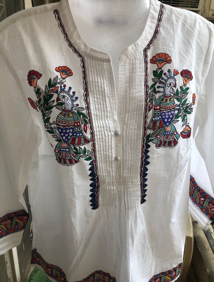 This is a beautiful, hand painted white kurta/kurti/traditional Indian pure cotton top. It has intricate colorful designs on a beautiful white base. It can be paired with jeans/pants or even your favorite skirt. Our artisan Rita painstakingly uses the traditional hand painted style called Madhubani from central India and it took her over a week to paint this unique top. The top is painted using a traditional Madhubani/Mithila technique from the Bihar state in India by our artisan, Rita who's fam Ethnic Kurti, Indian Tops, White Kurta, Unique Top, Yellow Painting, Cotton Tops, White Tops, White Painting, Pure Cotton