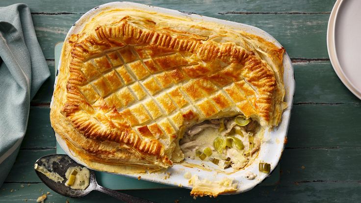 a pie sitting on top of a white plate next to a bowl and spoons