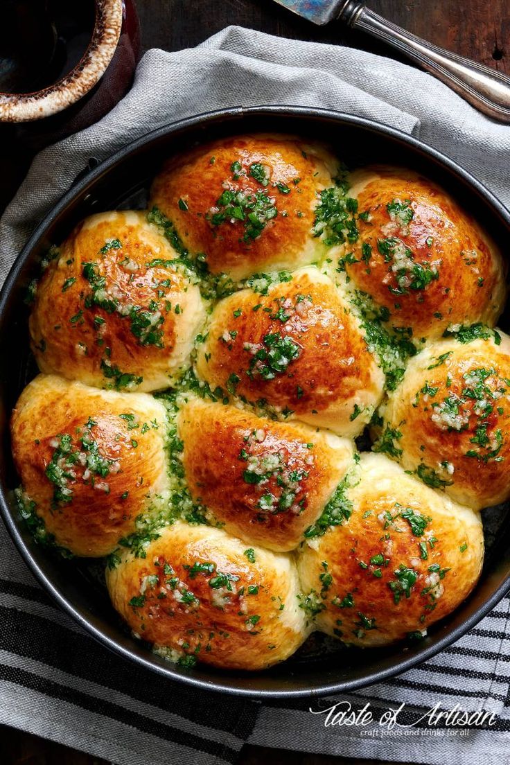 a pan filled with rolls covered in cheese and parsley