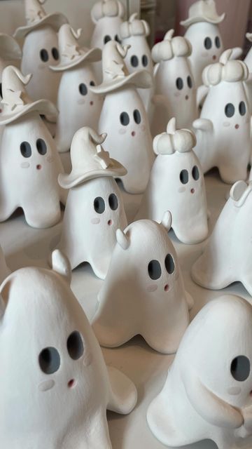 many white ghost figurines with black eyes and hats on top of each other