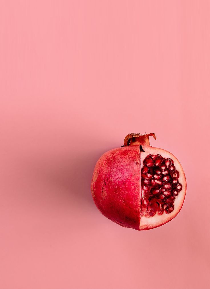 a pomegranate cut in half on a pink background