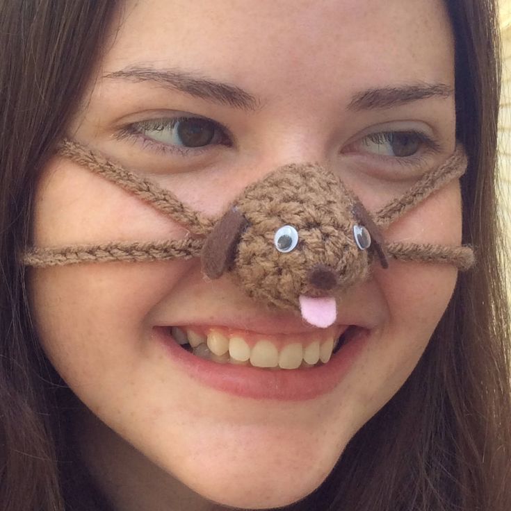 a woman is smiling with a dog's nose taped to her face and the eyes are made out of yarn