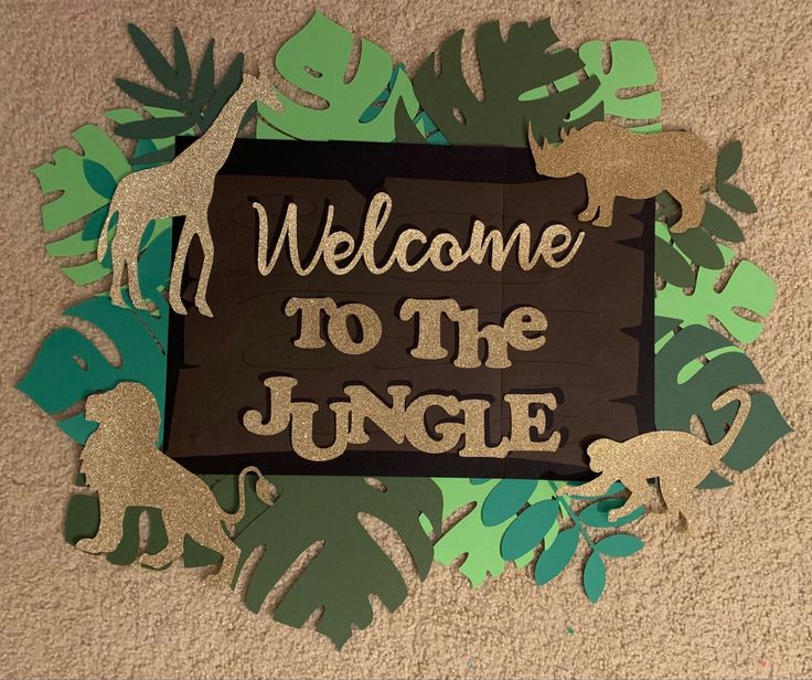 a sign that says welcome to the jungle with cut out animals and leaves around it