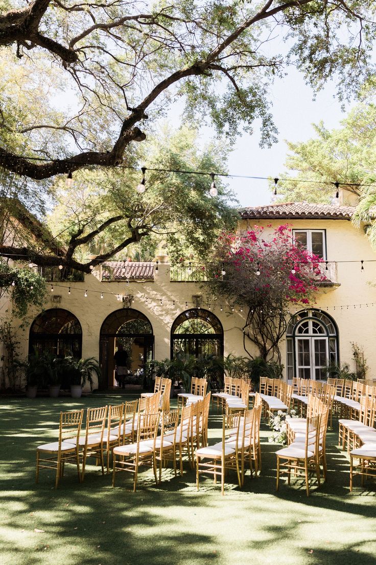 an outdoor venue with tables and chairs set up in front of the building, surrounded by trees