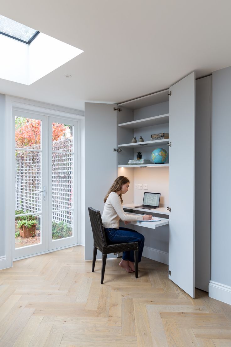 a woman sitting at a desk in front of a window with a laptop on it