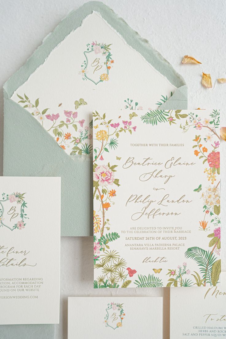 the wedding stationery is laid out on top of each other, with floral designs