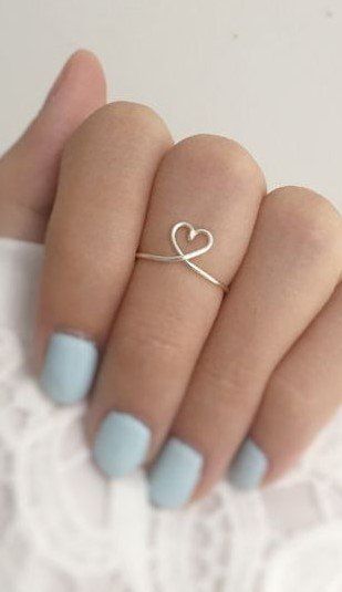 a woman's hand with a heart shaped ring on it