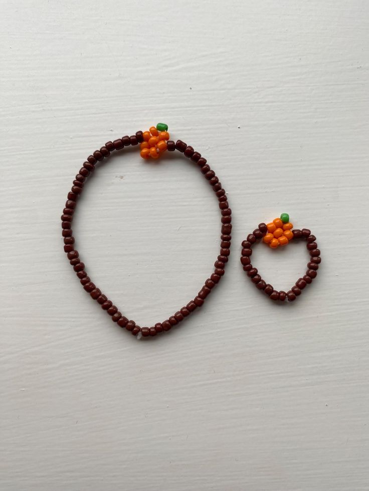 a beaded bracelet with an orange flower and two small beads on the end of it