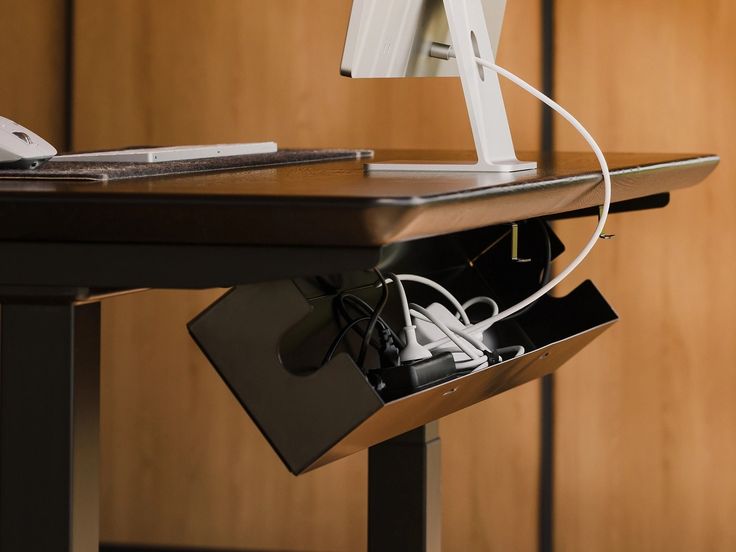 a desk with a computer monitor, keyboard and mouse connected to the side of it