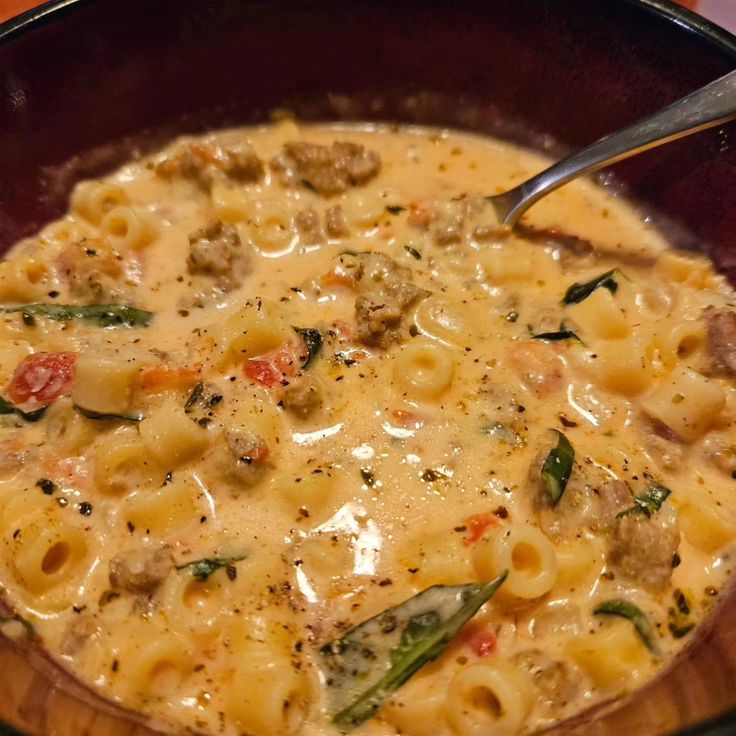 a close up of a bowl of food with pasta and meat in it on a table