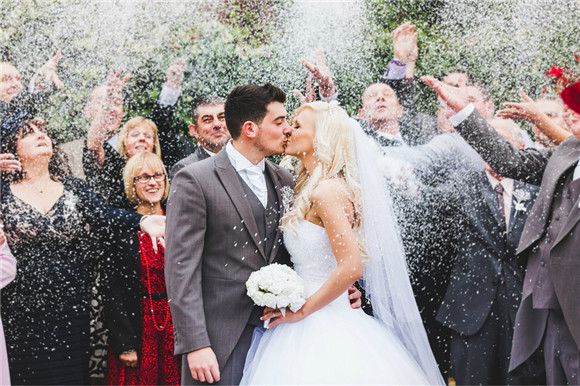 a newly married couple kissing in front of confetti thrown from their hands at them