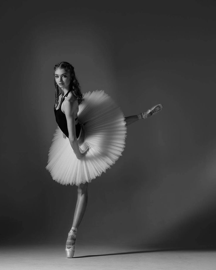 a young ballerina is posing for a black and white photo