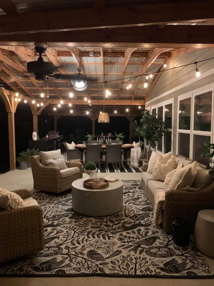 an outdoor living room with couches, tables and lights hanging from the rafters