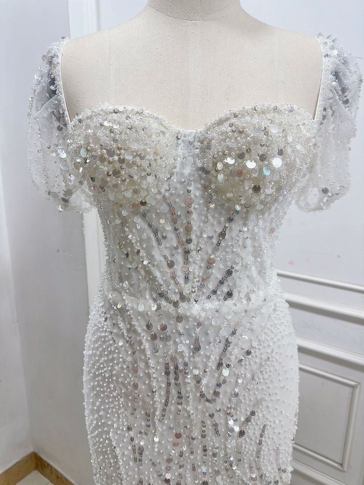 a white dress with silver sequins on the bust and shoulders, sitting on a mannequin