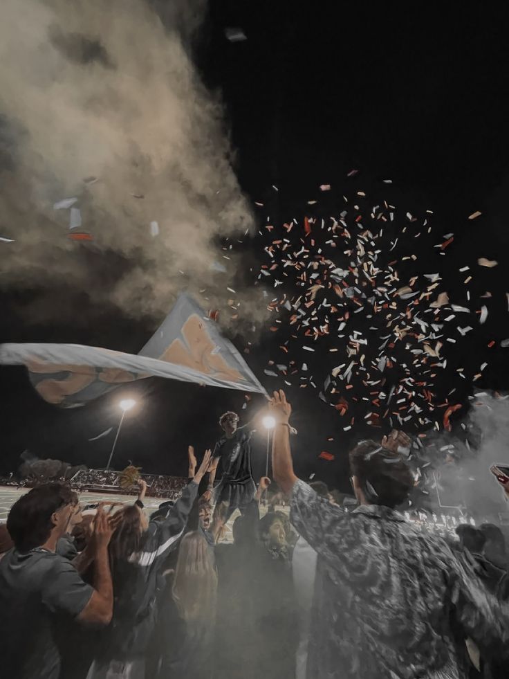 a group of people standing on top of a field under a sky filled with confetti