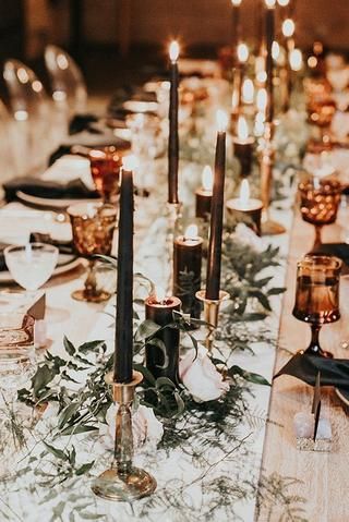 a long table with candles and greenery is set up for a formal dinner or party