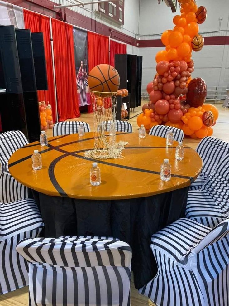 a basketball themed party with black and white striped chairs, orange balloons and wine glasses