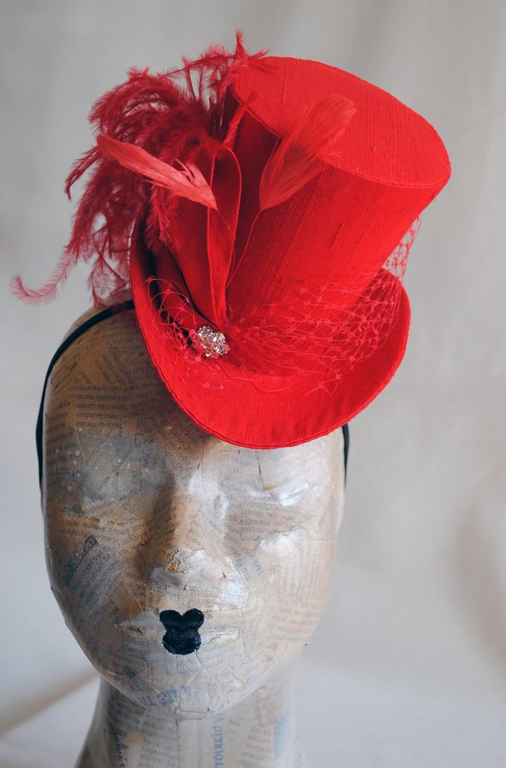 This striking yet elegant burlesque mini top hat is covered with beautiful bright red silk shantung. It is embellished with matching red veil, a luxurious spray of curled ostrich plums and a sparkling flower shaped rhinestone button. Also available in white,black and ivory here : https://www.etsy.com/shop/BizarreNoir?ref=seller-platform-mcnav&section_id=14329940 If you're interested in another color, please, send me a message to talk about your options. This mini top hat is fully lined with Elegant Fitted Hat For Halloween, Gatsby Style Mini Hat With Short Brim For Parties, Fitted Hats For Halloween Evening, Fitted Halloween Evening Hats, Short Brim Top Hat For Carnival Party, Fitted High Crown Hat For Costume Party, Vintage Fitted Headpieces For Party, Elegant Top Hat For Halloween Party, Vintage Party Top Hat