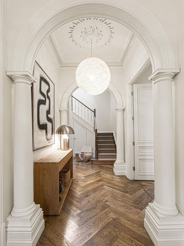 an entry way with wooden floors, white walls and large chandelier hanging from the ceiling