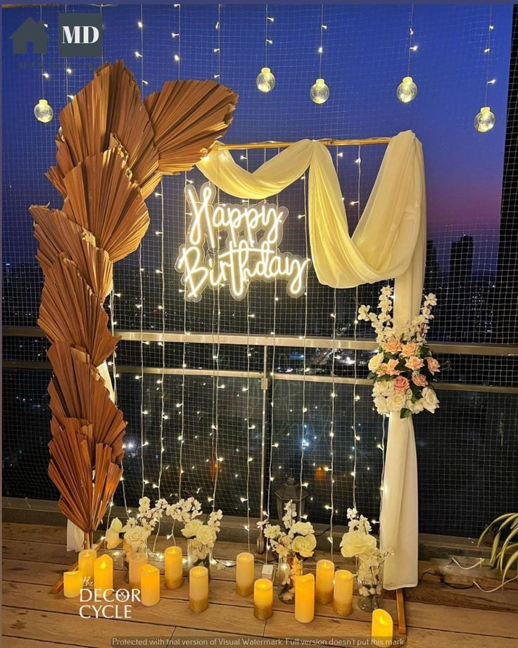 a happy birthday sign is lit up in front of a window with candles and flowers