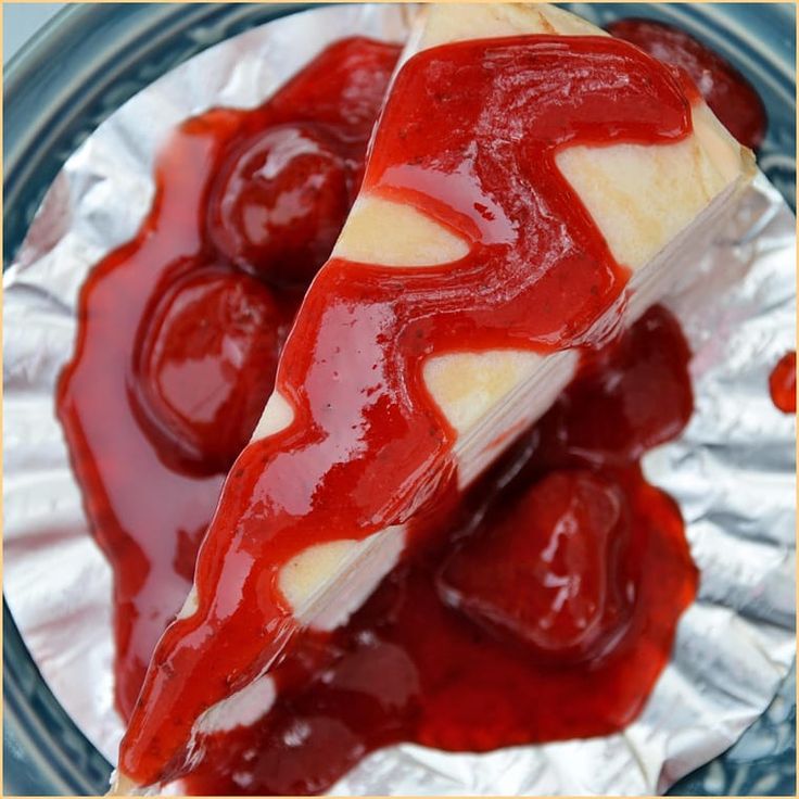 two slices of cheesecake covered in cherry sauce