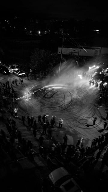 an aerial view of people standing in the middle of a circle at night with lights on