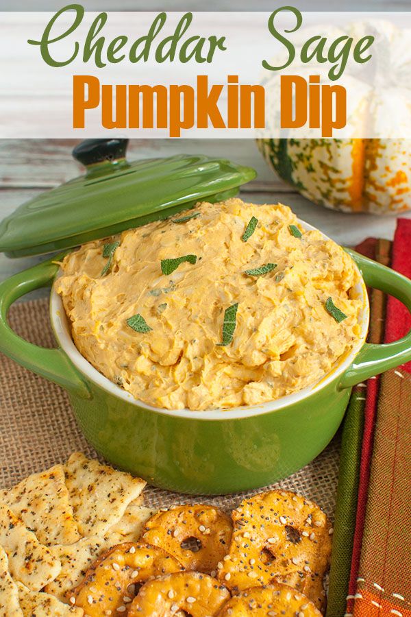 cheddar sage pumpkin dip in a green casserole dish with crackers