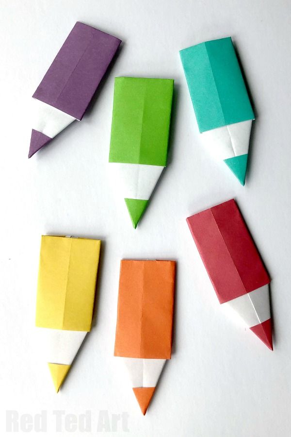 four different colored origami pencils are arranged on a white surface