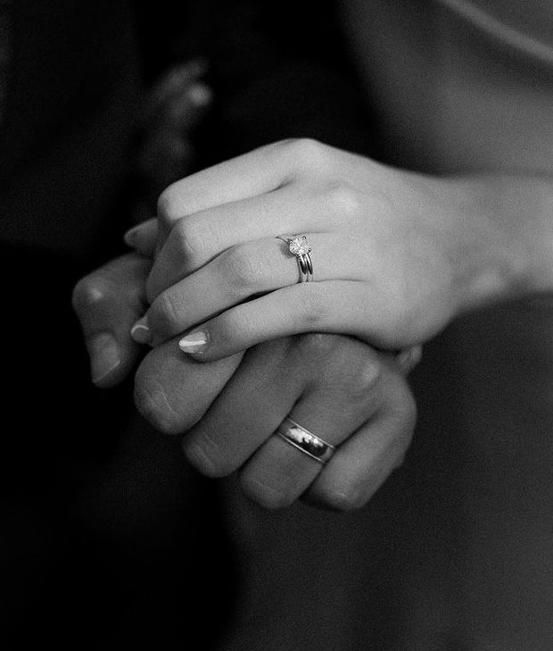 two hands holding each other with rings on their fingers, black and white photo in color