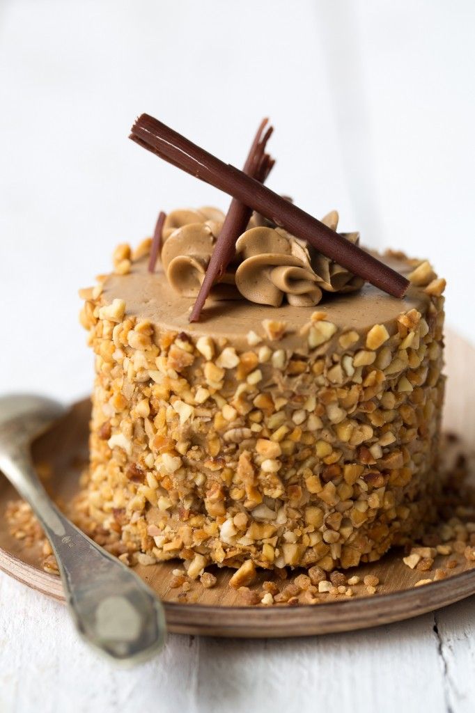 a cake with nuts and chocolate on top sitting on a plate next to a spoon