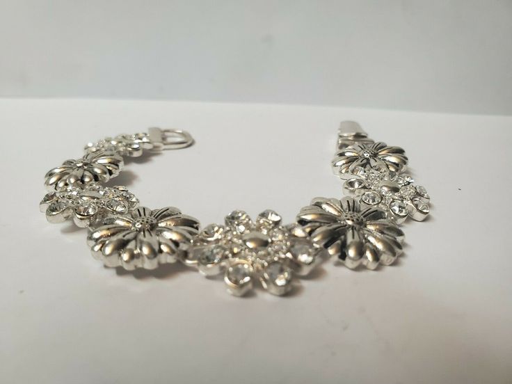 Vintage flowered bracelet silver tone bracelet antique jewelry. his is a lovely bracelet with silver & rhinestone flowered petals, unmarked. in good vintage condition. please all photos for details. thanks for looking and be sure to check out our other items! we have lots of vintage items, especially jewelry. we put new listings on daily so be sure to check back often. don't forget to add us to your favorites list! hughes-antique Vintage Silver Charm Bracelet For Wedding, Silver Flower Shaped Wedding Bracelet, Silver Flower Costume Jewelry, Vintage Flower Bracelets For Jewelry Making, Silver Bracelet With Flower Charm, Silver Bracelet Jewelry With Flower Charm, Vintage Silver Flower Bracelets, Silver Vintage Flower Bracelet, Nickel-free Silver Charm Bracelet For Wedding