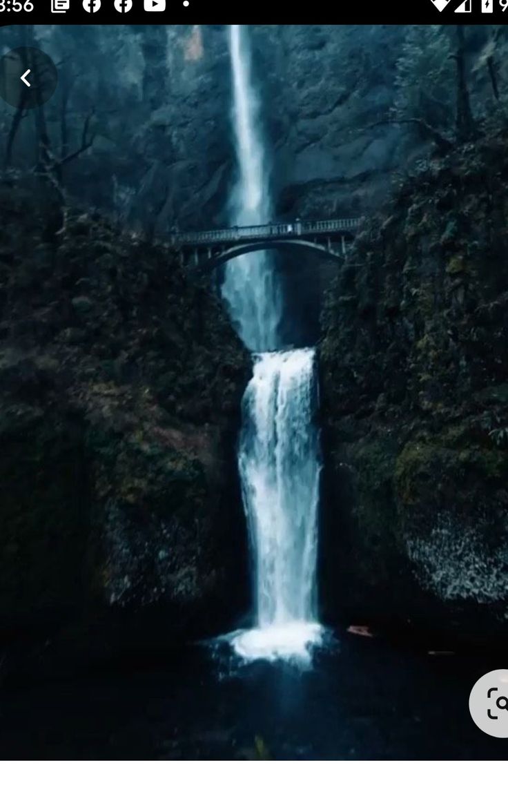 a large waterfall with a bridge over it