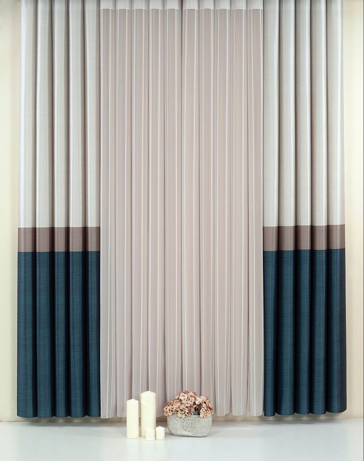 two candles are sitting on the floor in front of an open window with vertical blinds