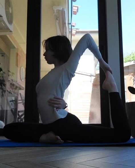 a pregnant woman doing yoga in front of a window