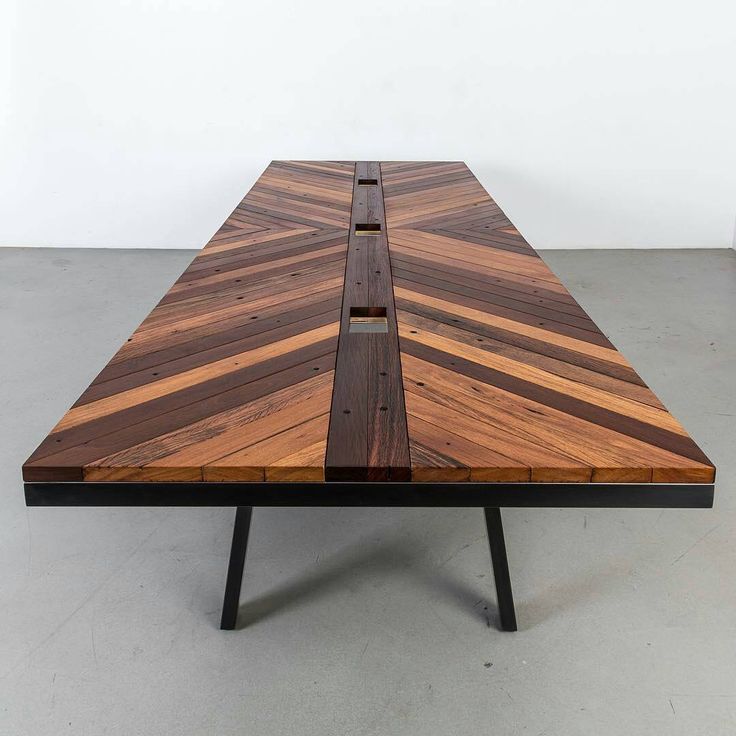 a wooden table sitting on top of a cement floor next to a white wall in an empty room