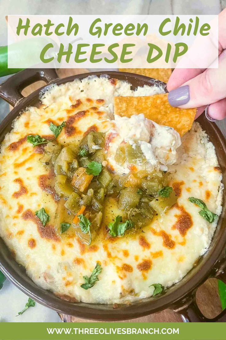 a bowl filled with cheese dip and tortilla chips next to a hand holding a chip