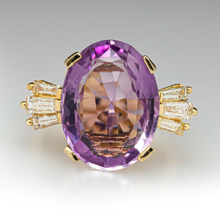 This exquisite ring is centered with one (1) oval mixed cut natural amethyst set into a four-prong setting. The shoulders of the ring are each accented with three (3), channel set, tapered baguette cut diamonds. The ring measures 15.9mm at the top, rises 9.4mm above the finger, tapering to 3.2mm wide and 1.3mm thick at the base of the shank. This ring is currently a size 6.25. Luxury Lavender Ring With Center Stone, Oval Purple Diamond Ring With Gemstone Accents, Oval Amethyst Ring With Gemstone Accents For Formal Occasions, Exquisite Oval Amethyst Ring For Wedding, Purple Baguette Cut Rings For Formal Occasions, Elegant Amethyst Marquise Ring, Luxury Lavender Ring With Prong Setting, Timeless Oval Purple Amethyst Ring, Exquisite Oval Amethyst Wedding Ring