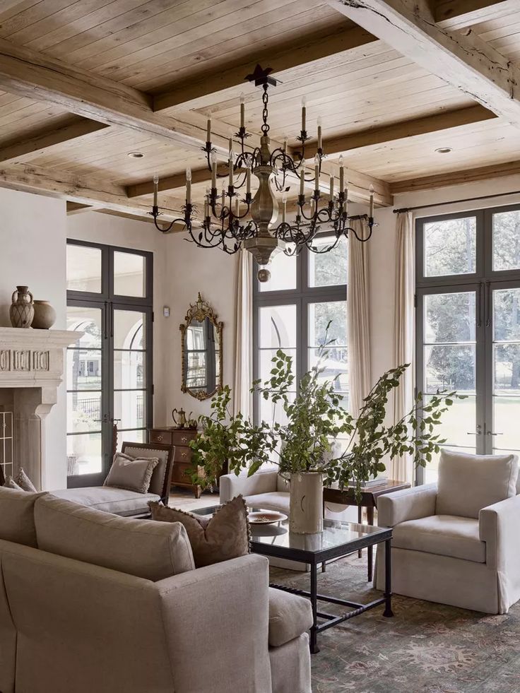 a living room filled with furniture and a chandelier hanging from the ceiling over a fire place