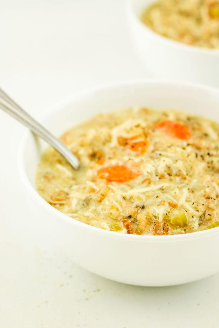 two bowls of soup with carrots and broccoli in them on a white surface