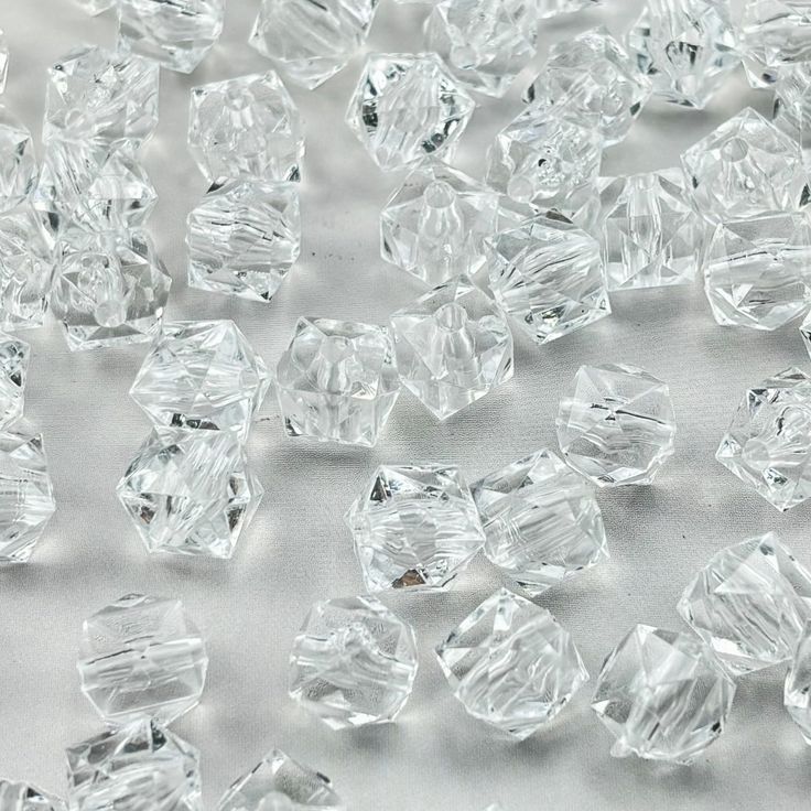 clear glass beads are scattered on a white surface