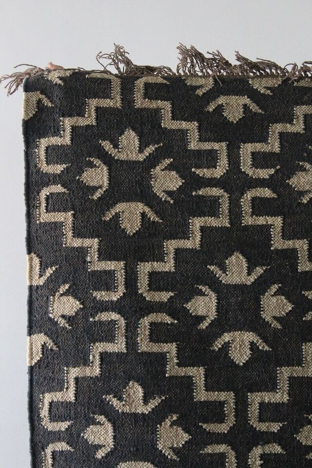 a black and beige rug with white designs on it