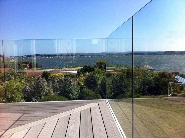 a deck with glass railing overlooking the water