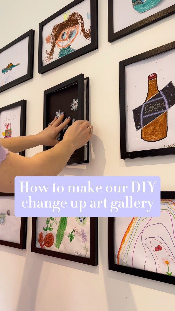 a woman is hanging pictures on the wall