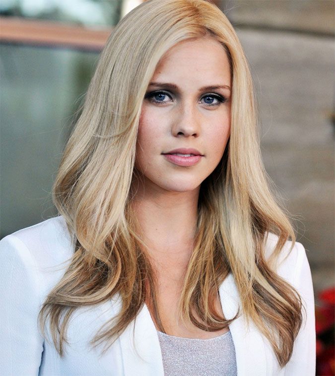 a woman with blonde hair and blue eyes is looking at the camera while wearing a white jacket